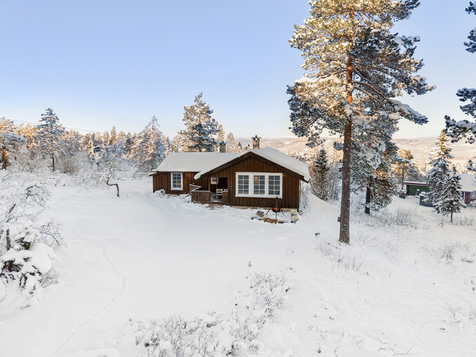 I naturskjønt vinterlandskap, ligger hytta solrikt og fint til, i lett skrånende terreng. Hytta har en smart vinkelutforming som gir en lun og koselig terrasseplass skjermet for vær og vind. Galleribilde