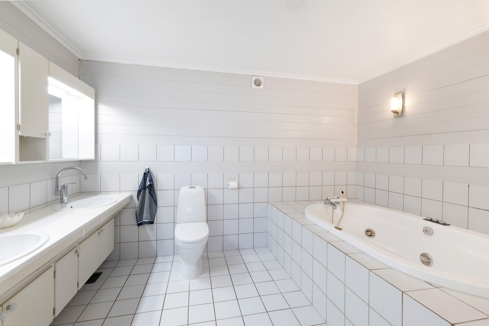 Bad 1 med badekar, toalett og dobbelvask. Fliser på gulv med varmekabler. Flis/panel på vegg. Veggene(panel) med våtromsmaling. Galleribilde