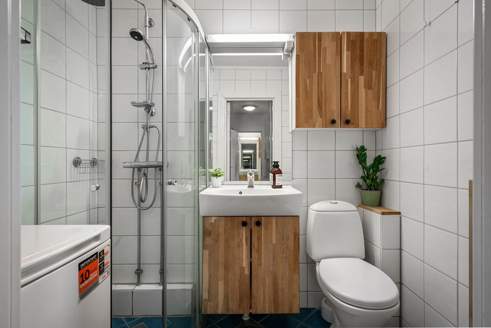 Flislagt baderom med gulvvarme og opplegg for vaskemaskin. Regnfalldusj og vanlig dusjhode Galleribilde