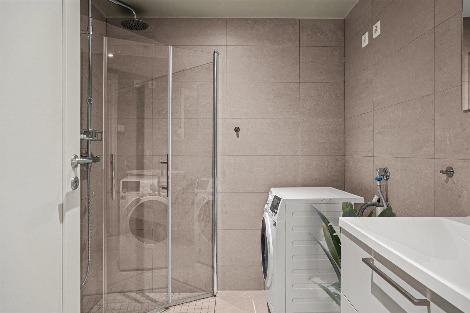 Rommet har innredning med nedfelt servant, veggmontert toalett, dusjvegger/hjørne og opplegg for vaskemaskin. Galleribilde