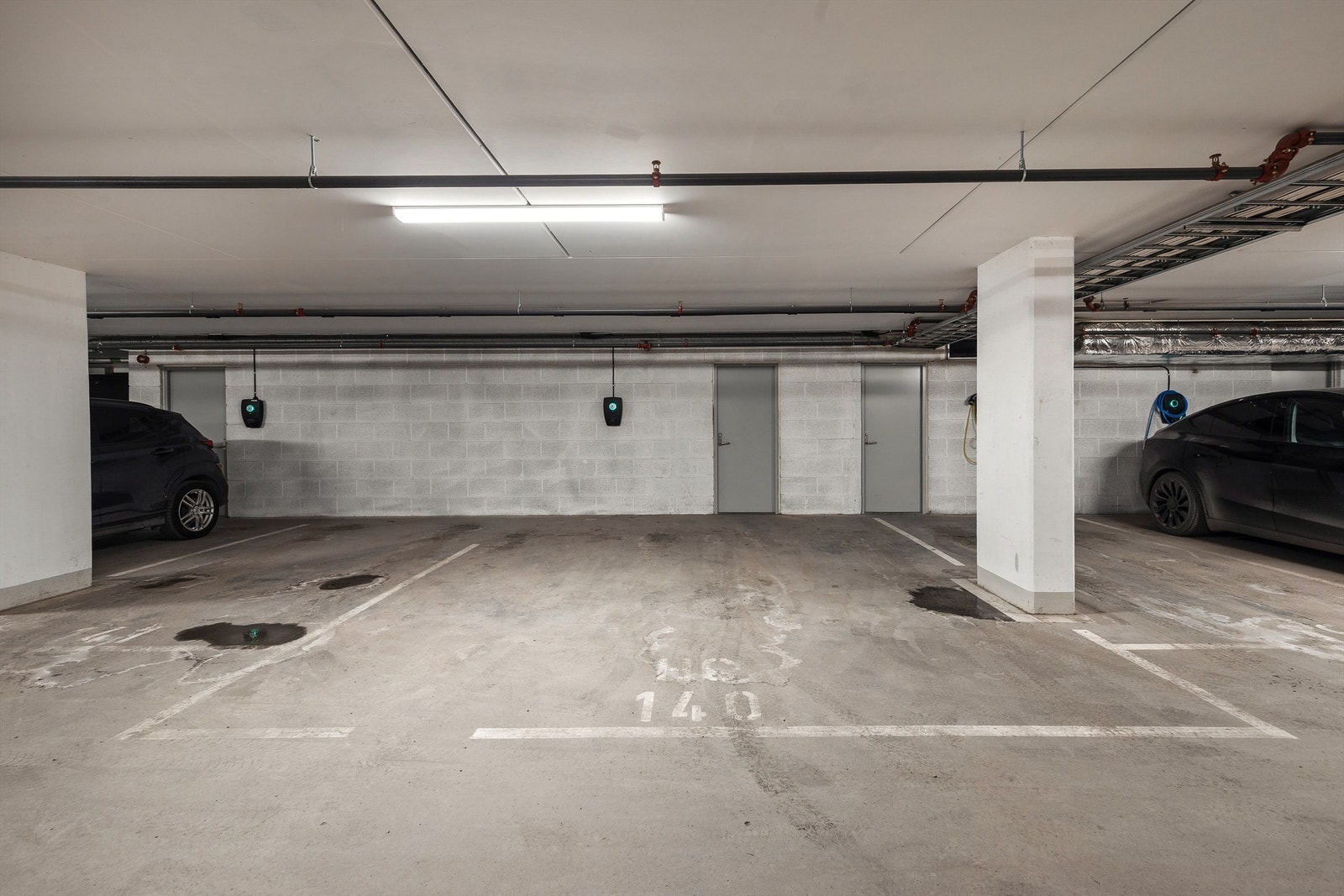 Stor parkeringsplass i lukket garasjeanlegg med lader for elbil montert. Galleribilde