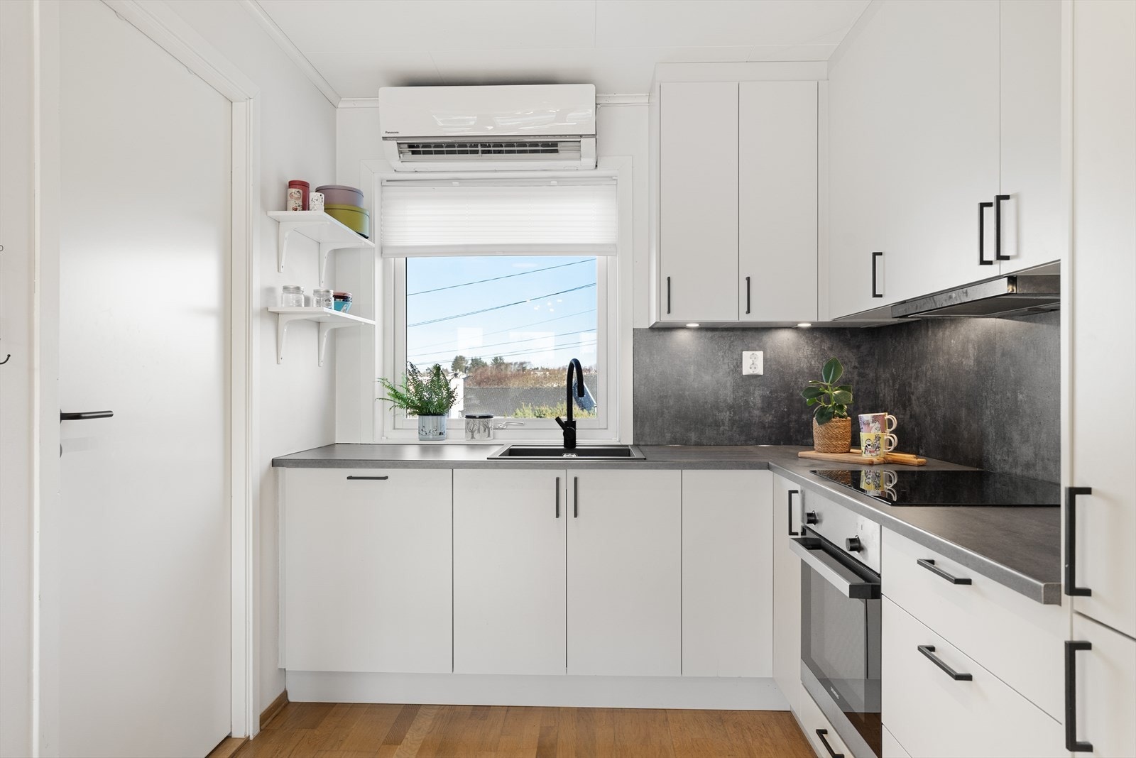 Kjøkkenet har hvite, slette fronter og laminat benkeplate med nedfelt servant Galleribilde