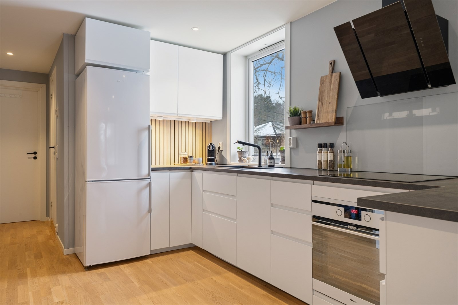 Kjøkkenet har en innredning med slette fronter fra 2018, laminat benkeplate og belysning under overskap. Galleribilde