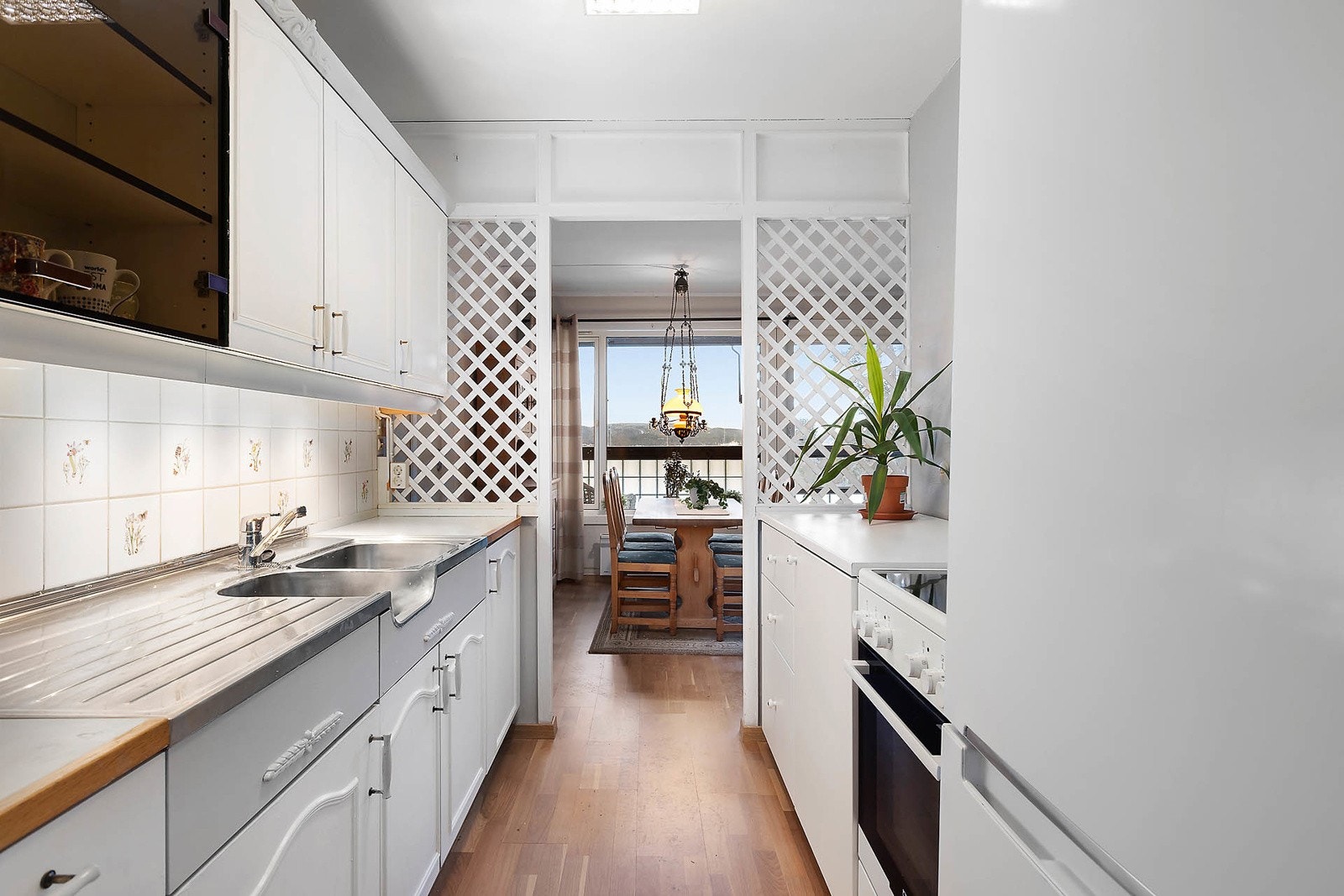 Kjøkken med glatte malte skapfronter med dekorlist, laminat benkeplate med fliser på bakvegg. Galleribilde