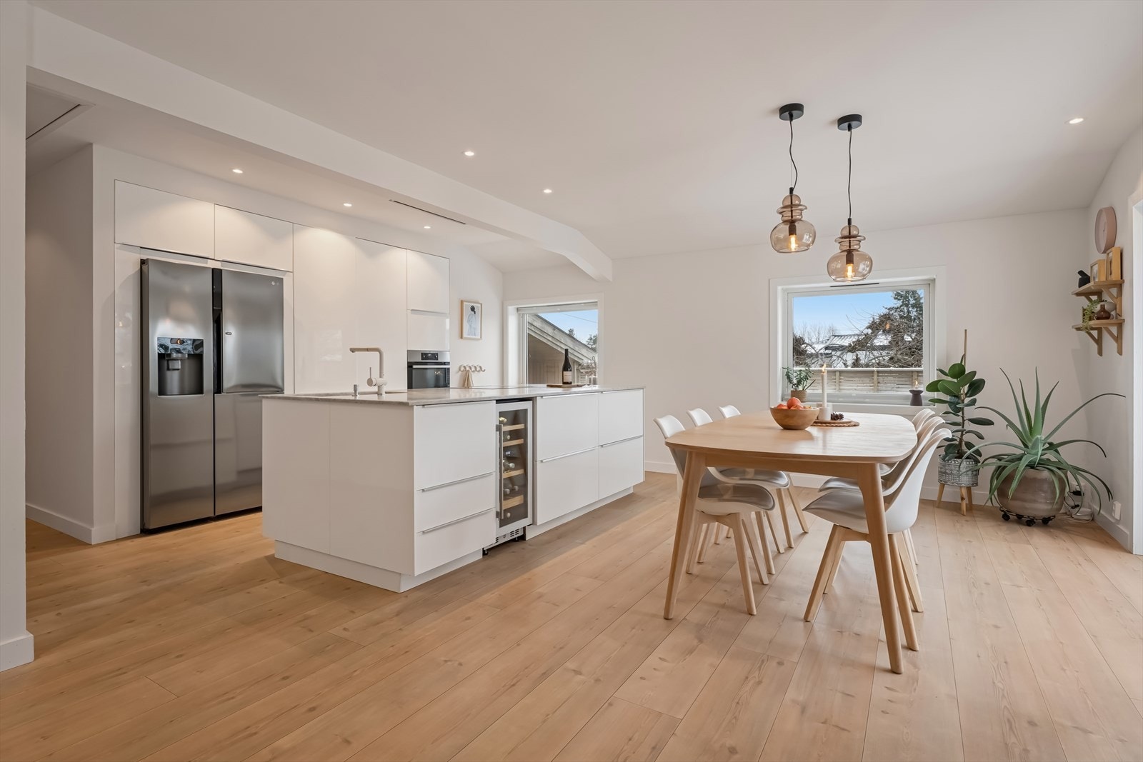 Kjøkkenet er fra 2014 og fremstår moderne og stilrent, med glatte hvite fronter og steinbenkeplate med planlimt kum i rustfritt stål Galleribilde