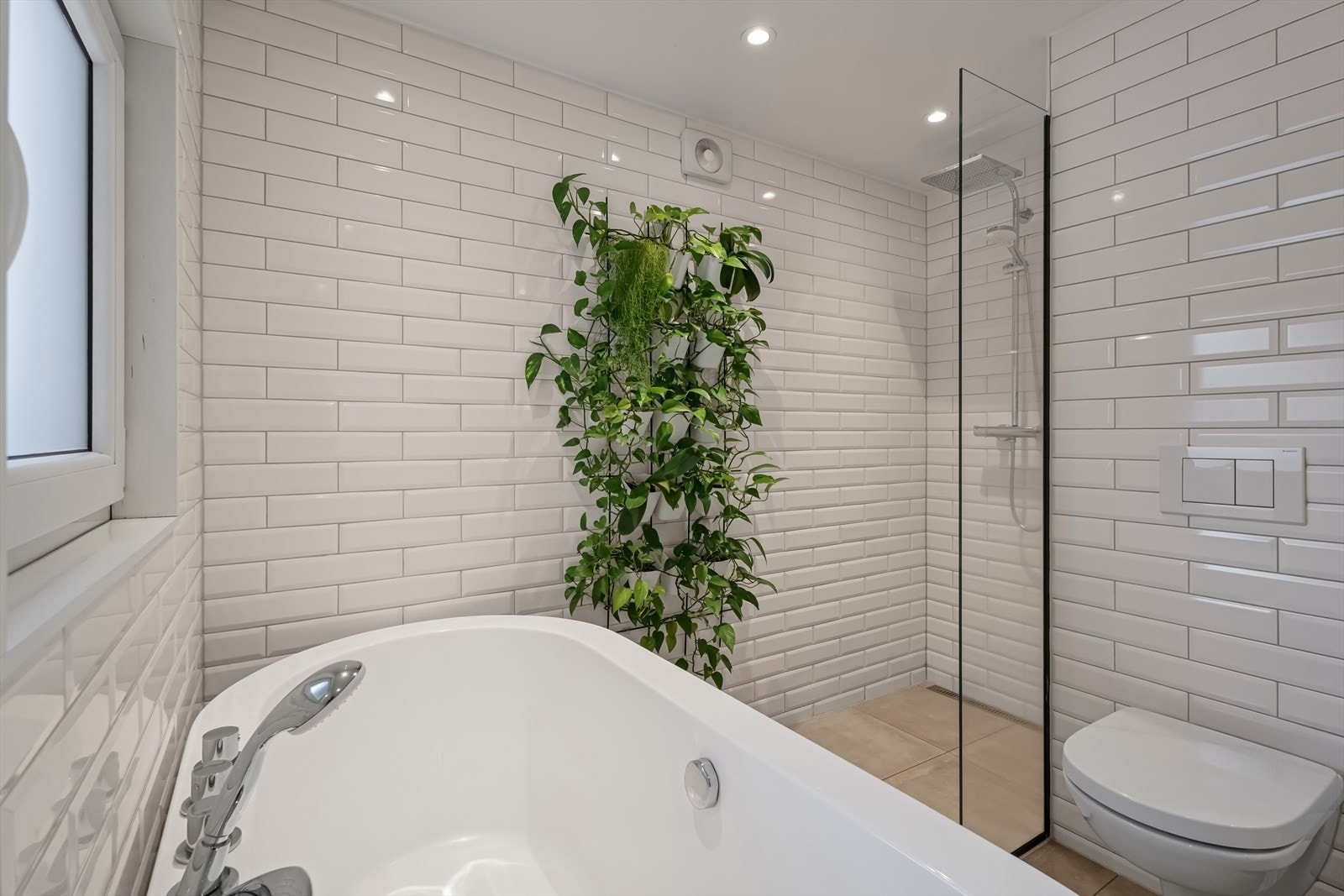 Sanitærutstyret omfatter vegghengt toalett, en romslig dusjnisje med glassvegg og et stilfullt badekar som inviterer til avslappende stunder Galleribilde