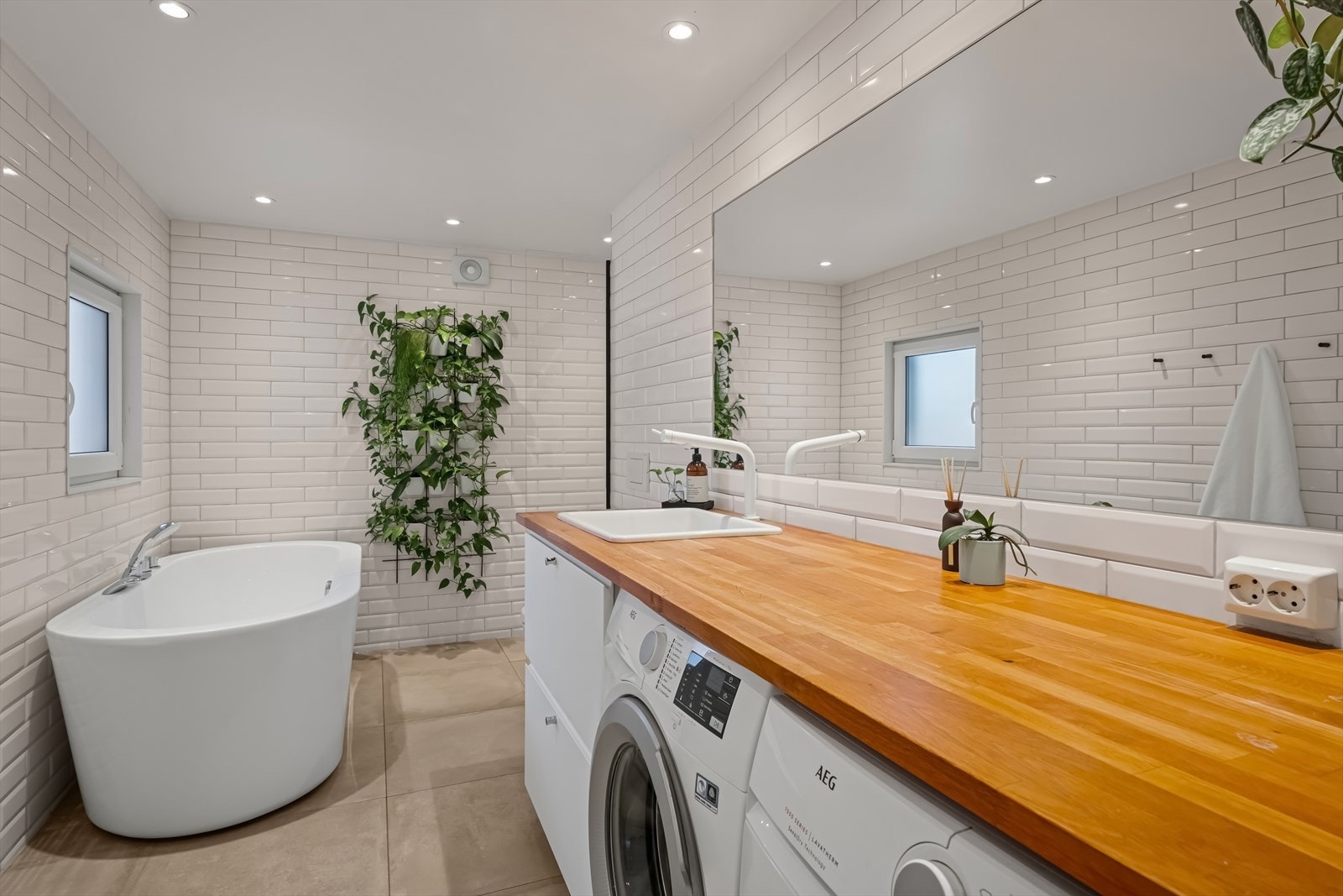 Baderomsinnredningen består av en heldekkende benkeplate med nedfelt hvit servant, skuffeseksjon med glatte fronter og et stort, innfliset speil Galleribilde