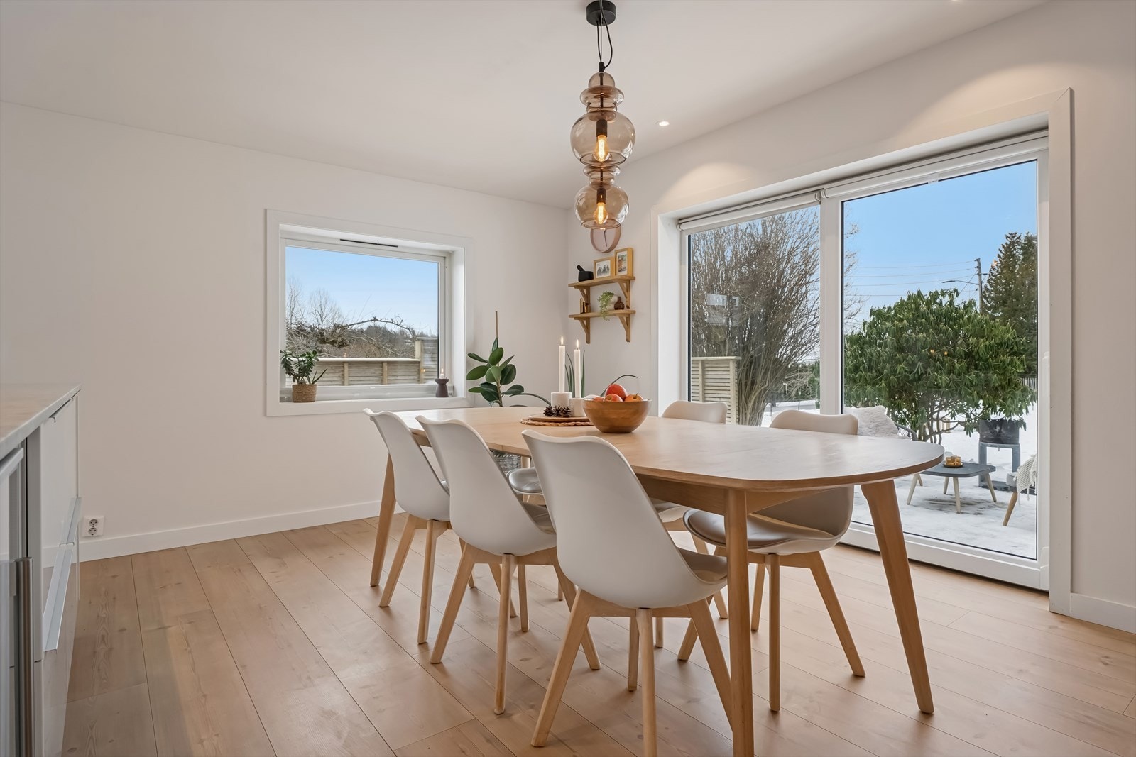 Fra stuen leder skyvedører ut til en solrik hage og markterrasse med terrassebord og levegg i liggende kledning Galleribilde