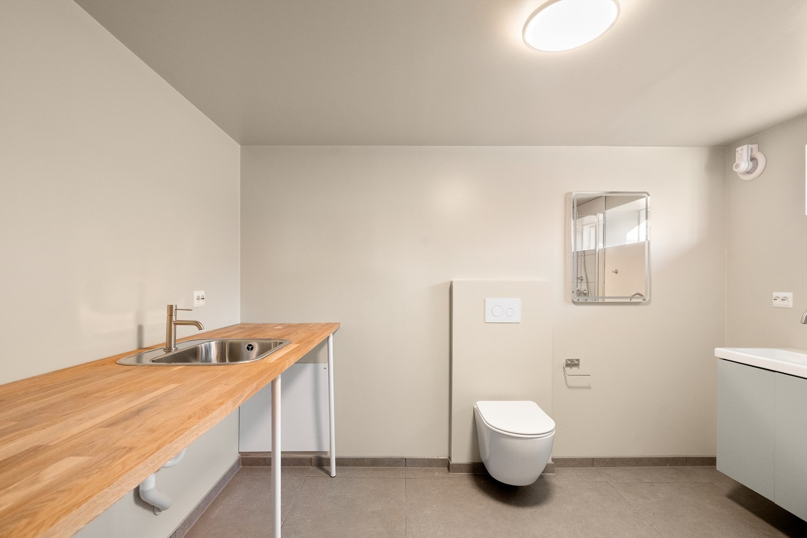 Innredet vaskerom i kjeller med stor arbeidsbenk og plass samt opplegg for vaskemaskin og tørketrommel. Galleribilde