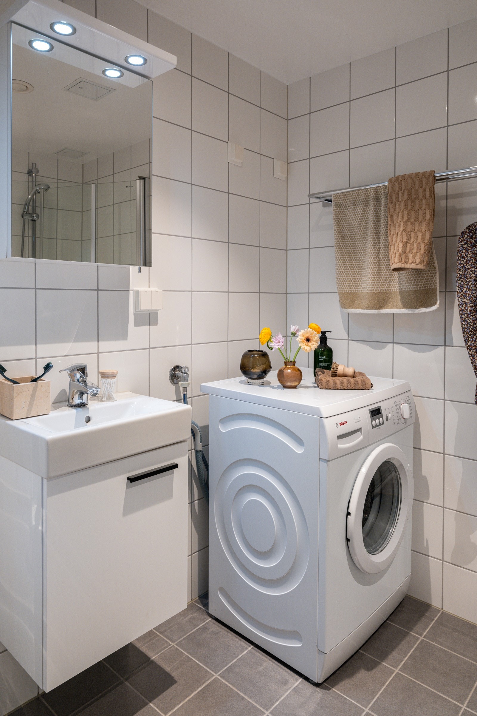 Baderommet er utstyrt med lyst servantskap med speilskap og belysning over, dusjhjørne med innfellbare glassdører og vegghengt toalett. Galleribilde