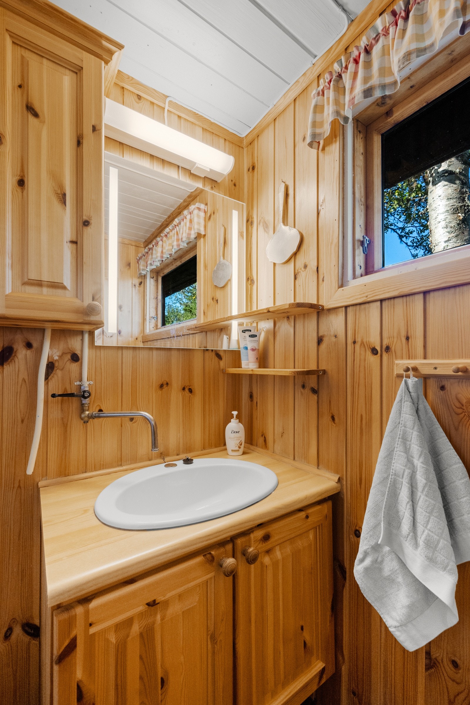 Badet er enkelt, med belegg på gulv og panel på veggene Galleribilde