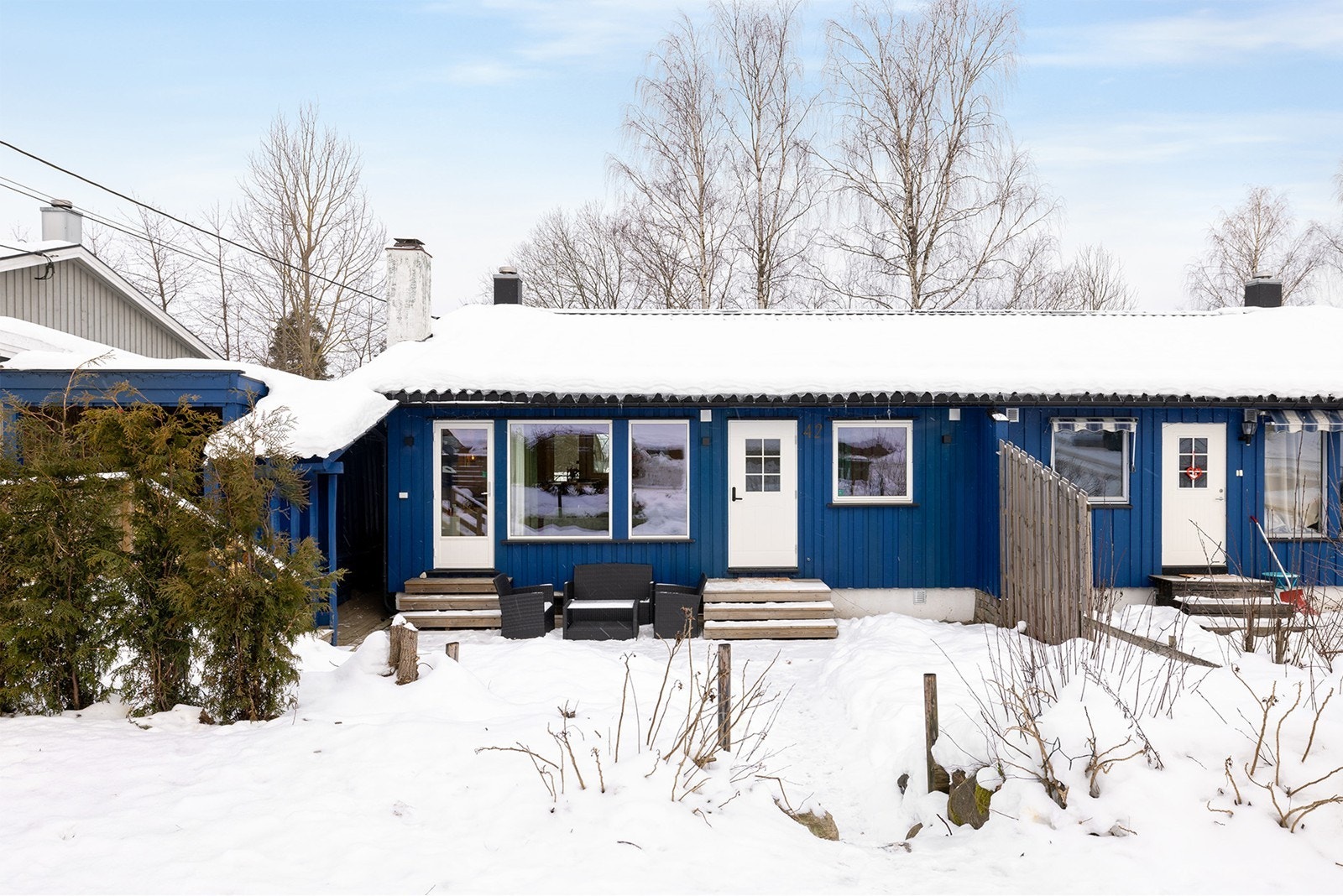 Fasade, fremside. Her har en tilgang fra parkeringsplass og carport med lader (til venstre i bildet), samt en naturlig trapp av stein foran inngangsdør. Galleribilde