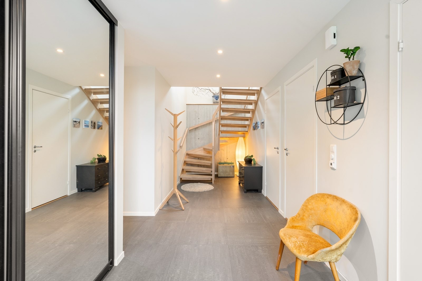 Stor praktisk hall med fliser på gulv. Skyvedørsgarderobe i sorte detaljer med speil. Galleribilde