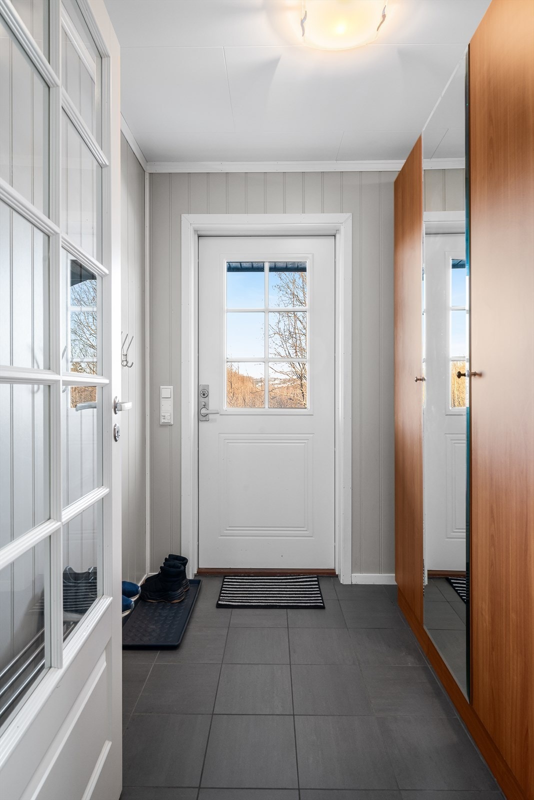 Romslig entre med flis på gulv og garderobe Galleribilde