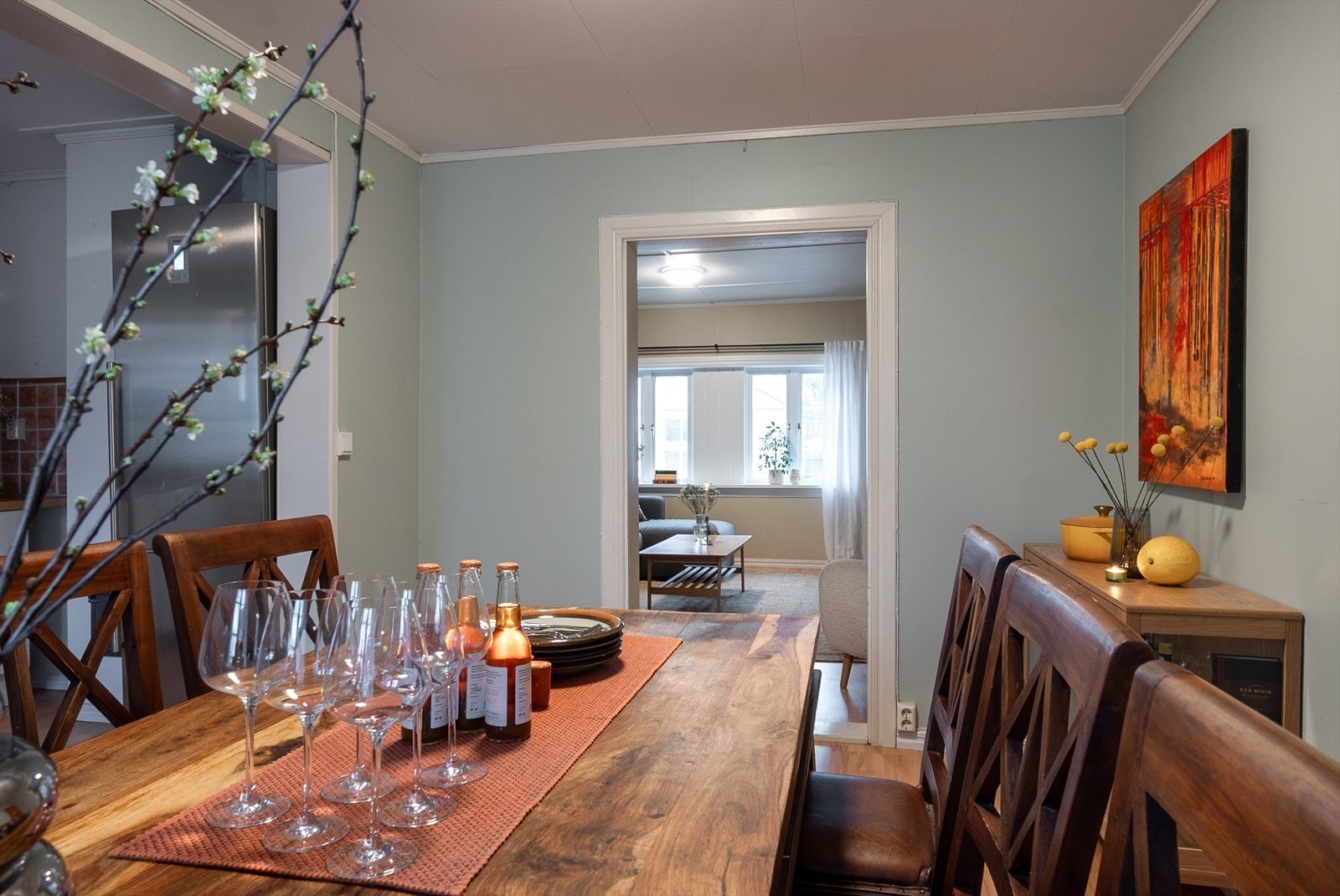 Spisestuen ligger i tilknytning til kjøkkenet, med svakt grønnfargede vegger og profilert listverk. Innenfor venter dagligstuen med tilsvarende duse vegger, god atmosfære og en peisovn. Galleribilde