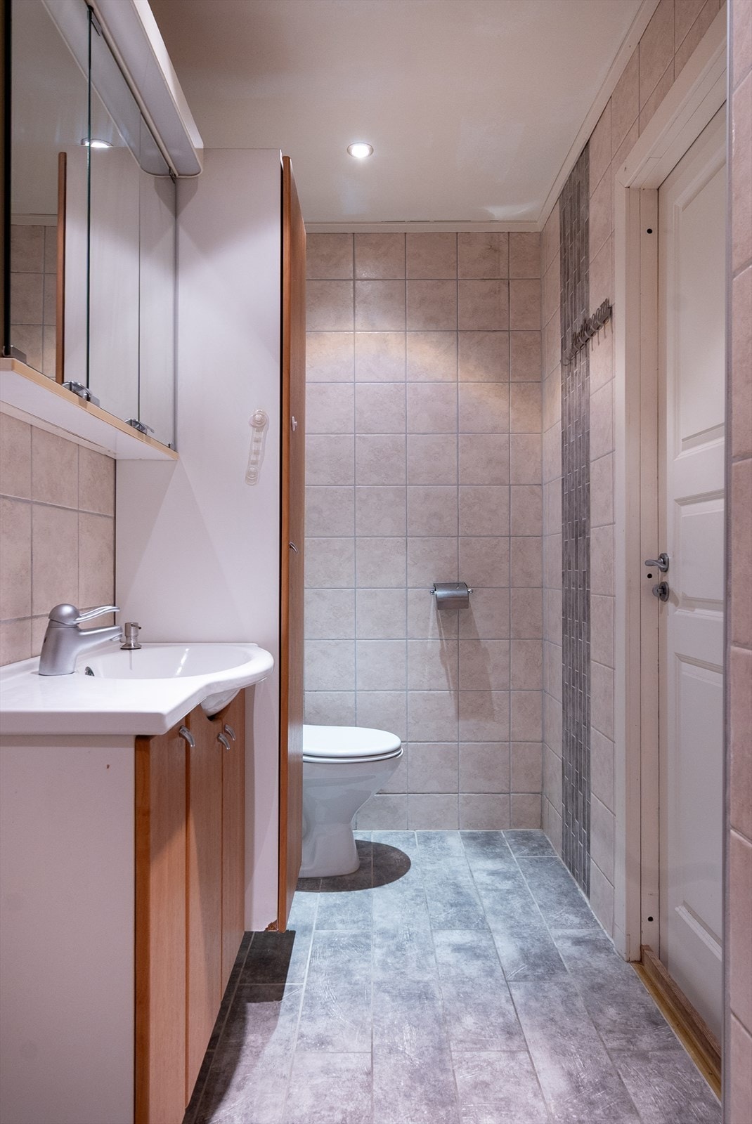 Badet i andre etasje er helfliset i varme, nøytrale toner, med servantskap og høyskap i nøttebrune fronter. Galleribilde