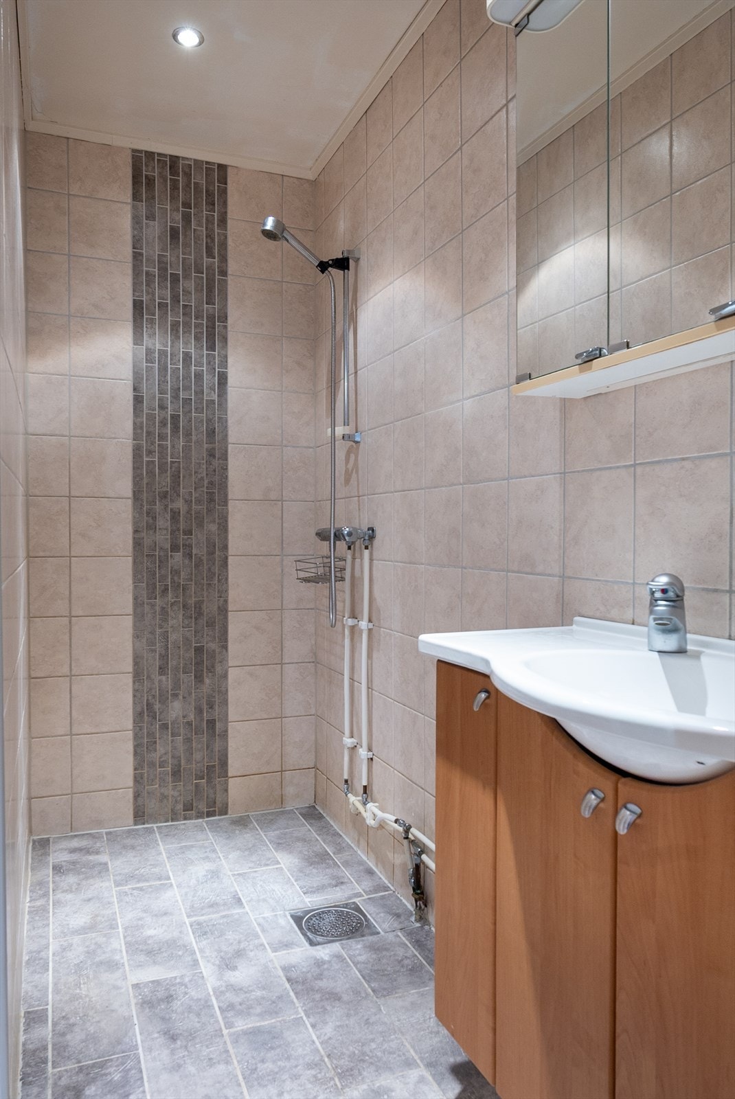 Badet i andre etasje er helfliset i varme, nøytrale toner, med servantskap og høyskap i nøttebrune fronter. Galleribilde