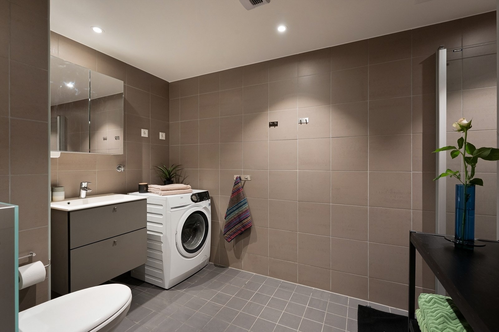 Lekkert, flislagt bad med gulvvarme, utført i mørke, tidløse fliser som skaper en lun og behagelig atmosfære. Galleribilde