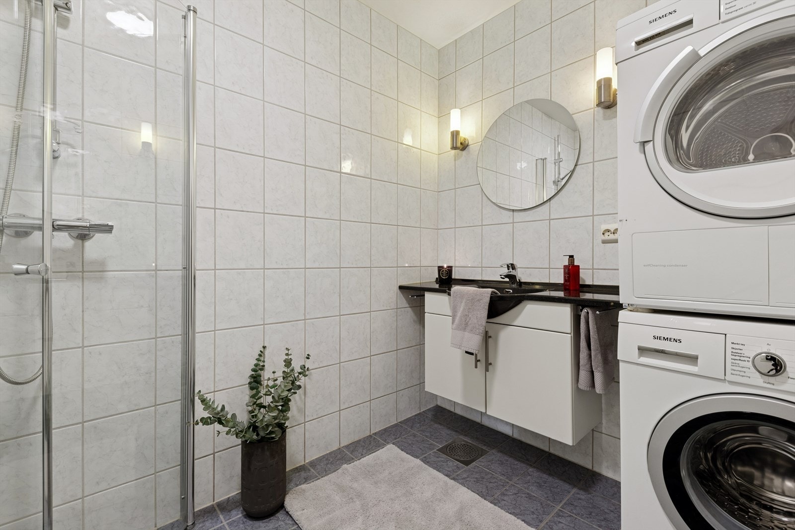 Badet er flislagt, med vegghengt baderomsmøbel og opplegg til vaksemaskin. Galleribilde