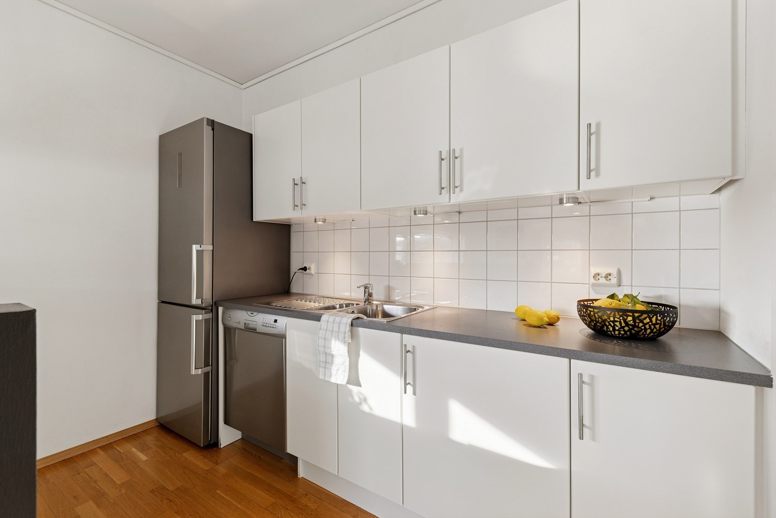 Kjøkkenet har hvite, slette fronter og benkeplate av laminat. Galleribilde