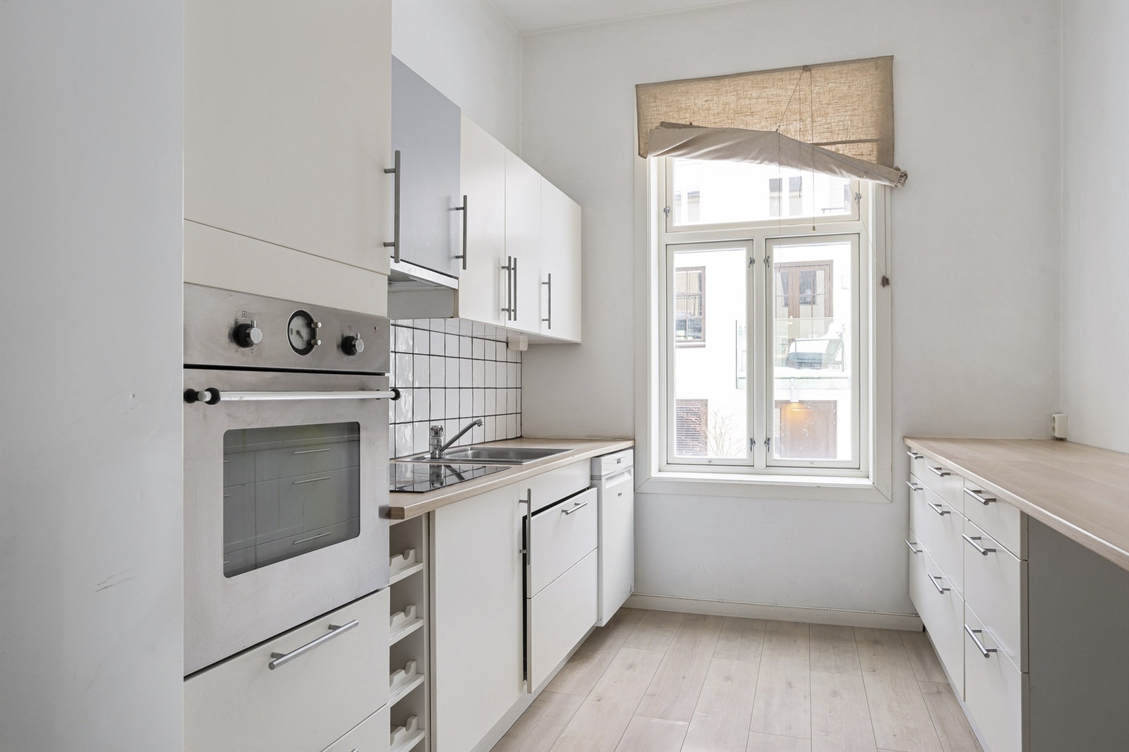 Praktisk kjøkken med hvite fronter og barløsning for spiseplass. Galleribilde