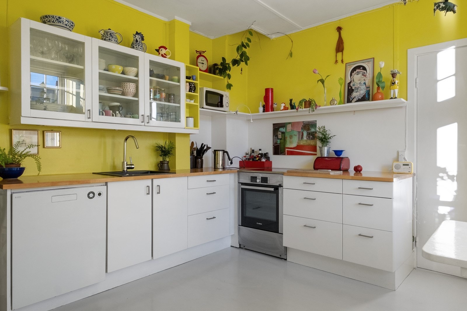 Kjøkkeninnredning med glatte fronter og laminat benkeplate med nedfelt vaskekum. Det er opplegg for oppvaskmaskin og plass til frittstående hvitevarer. Galleribilde