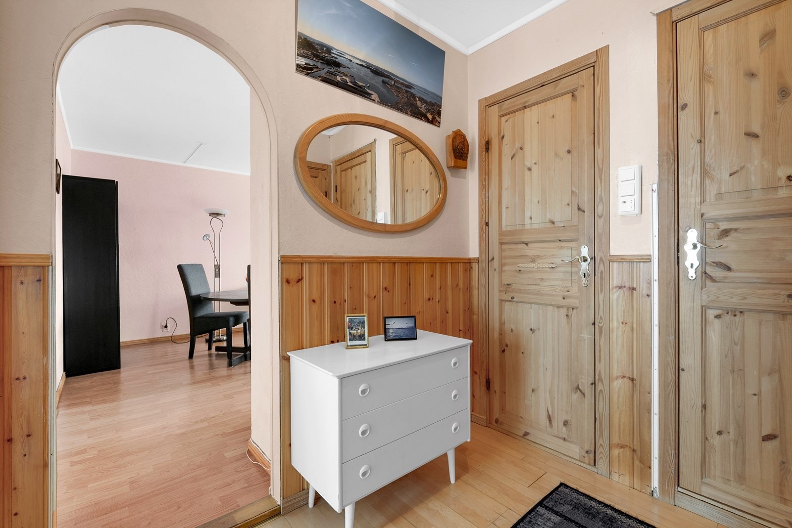 Romslig entré med parkettgulv og brystningspanel som leder videre inn i leiligheten. Galleribilde