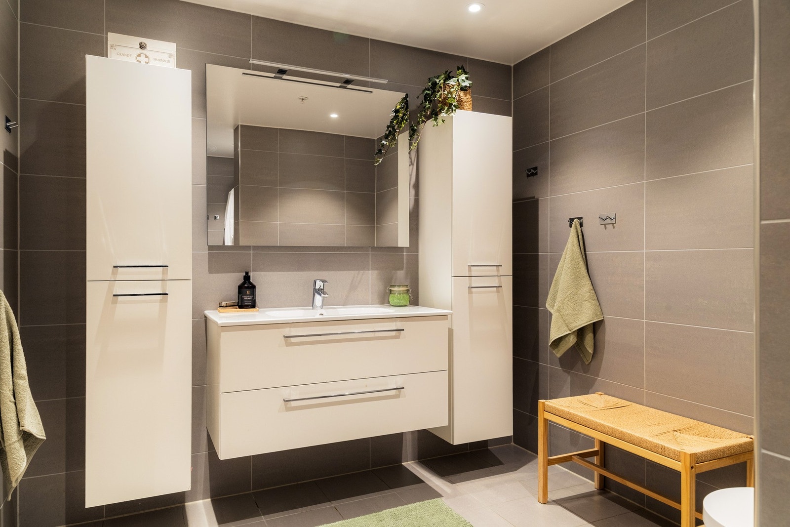 Rommet er innredet med vegghengt servantskap med skuffer, ovenpåliggende servant, speil med belysning samt to praktiske høyskap Galleribilde