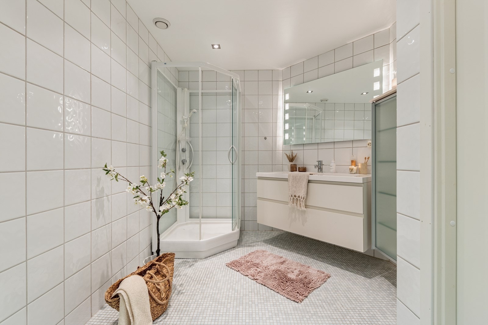 Badet er innredet med speil, servant med seksjon, dusjkabinett og vegghengt toalett. Galleribilde