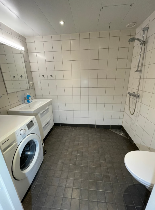 Flislagt bad med dusj, vaskemaskin og praktiske oppbevaringsløsninger. Galleribilde