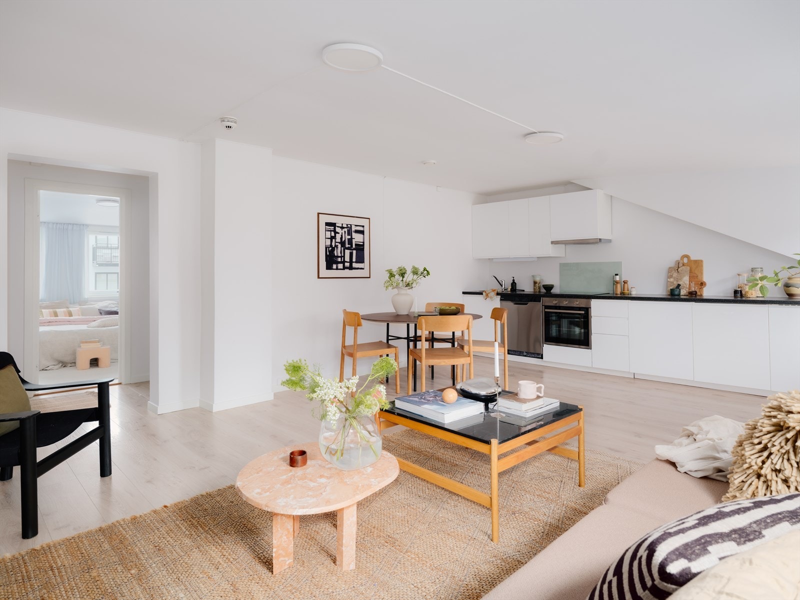 Kjøkken i åpen løsning mot stue skaper en sosial og åpen atmosfære. Innredningen har en tidløs kombinasjon av hvite matte fronter med integrert grep og sort benkeplate. Galleribilde