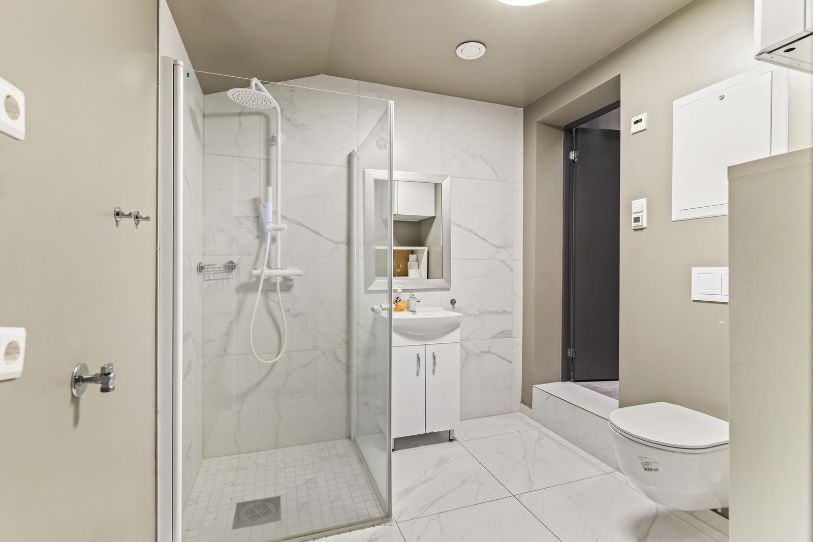 Pent bad i 1. etasje fra 2022 med flislagt gulv med varme. Her er det også opplegg for vaskemaskin. Badet har også en egen ytterdør via gang. Galleribilde