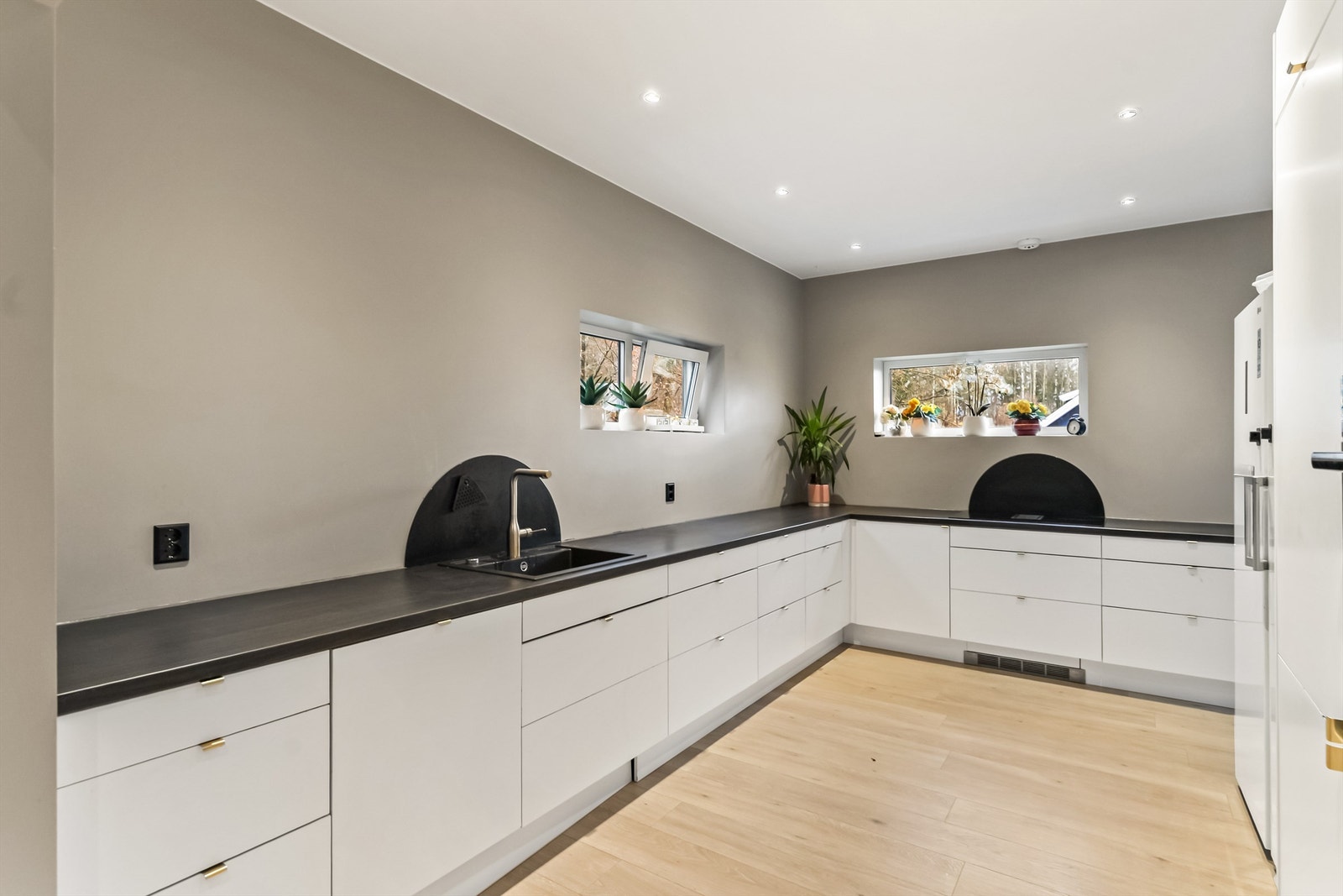 Kjøkken i hovedetasjen har delvis åpen løsning mot den romslige stuen. Kjøkkeninnredningen ble montert i 2023 og har slette, moderne fronter og benkeplater av laminat. Her får du rikelig med skap- og benkeplass. Galleribilde