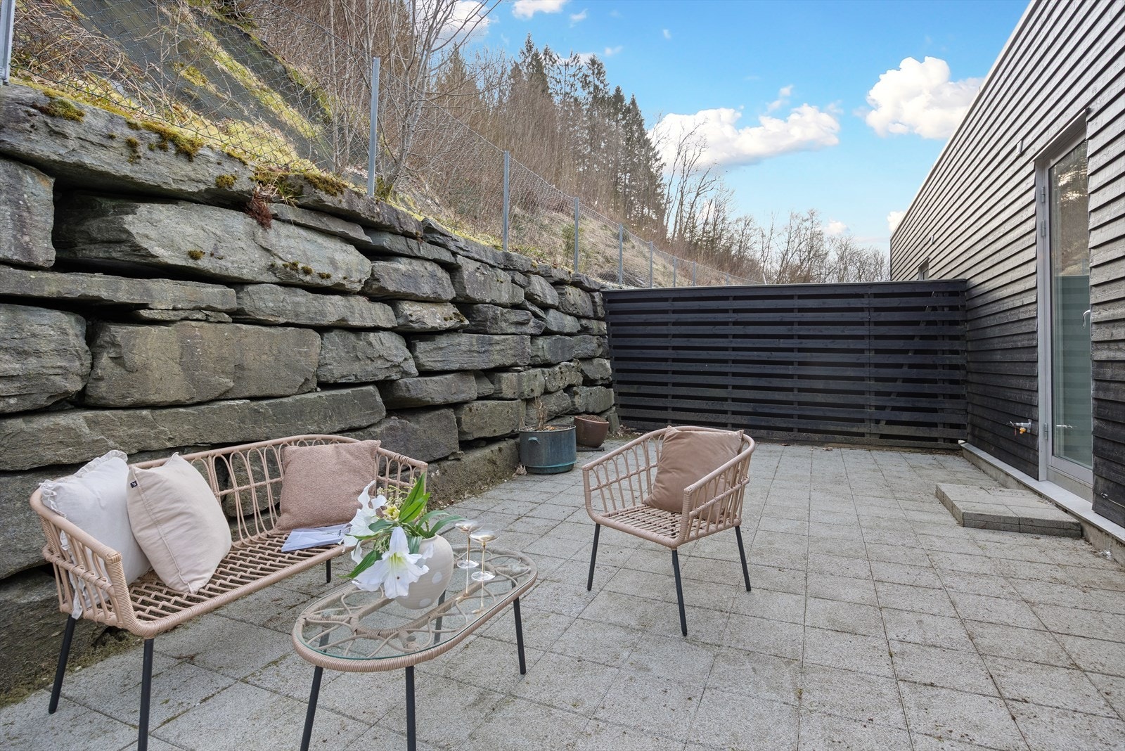 Stor steinlagt uteplass med plass til innredning av sittegrupper og annet terrassemøblement. Galleribilde