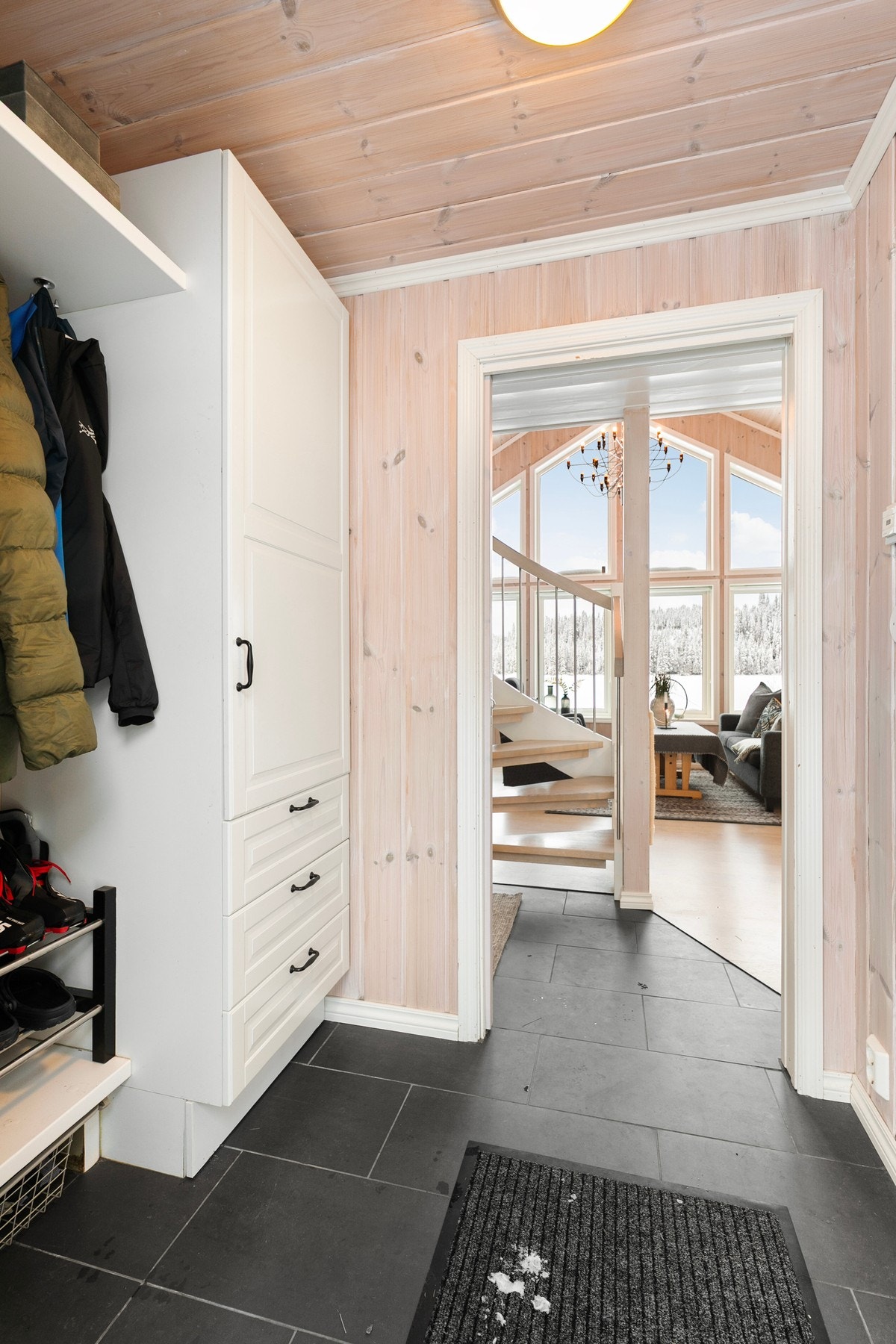 Lys og innbydende entre med fliser på gulv med gulvvarme og panel på vegger. Galleribilde