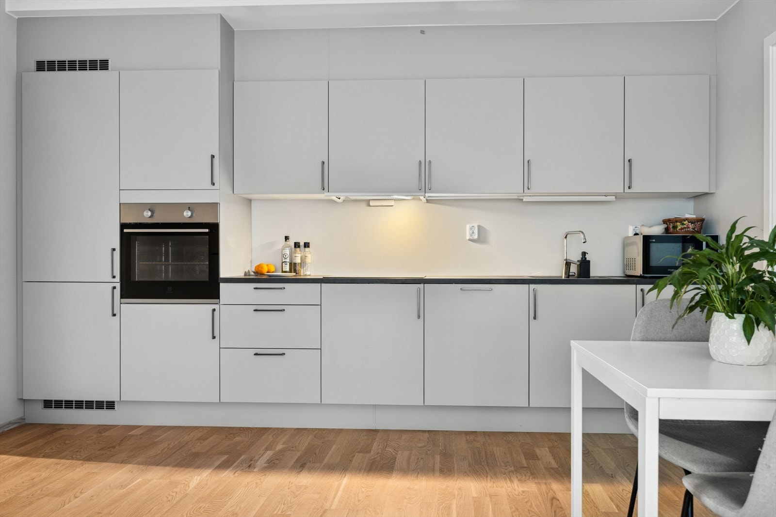 Kjøkkeninnredningen har glatte, lyse fronter og integrert stekeovn i god arbeidshøyde. Galleribilde