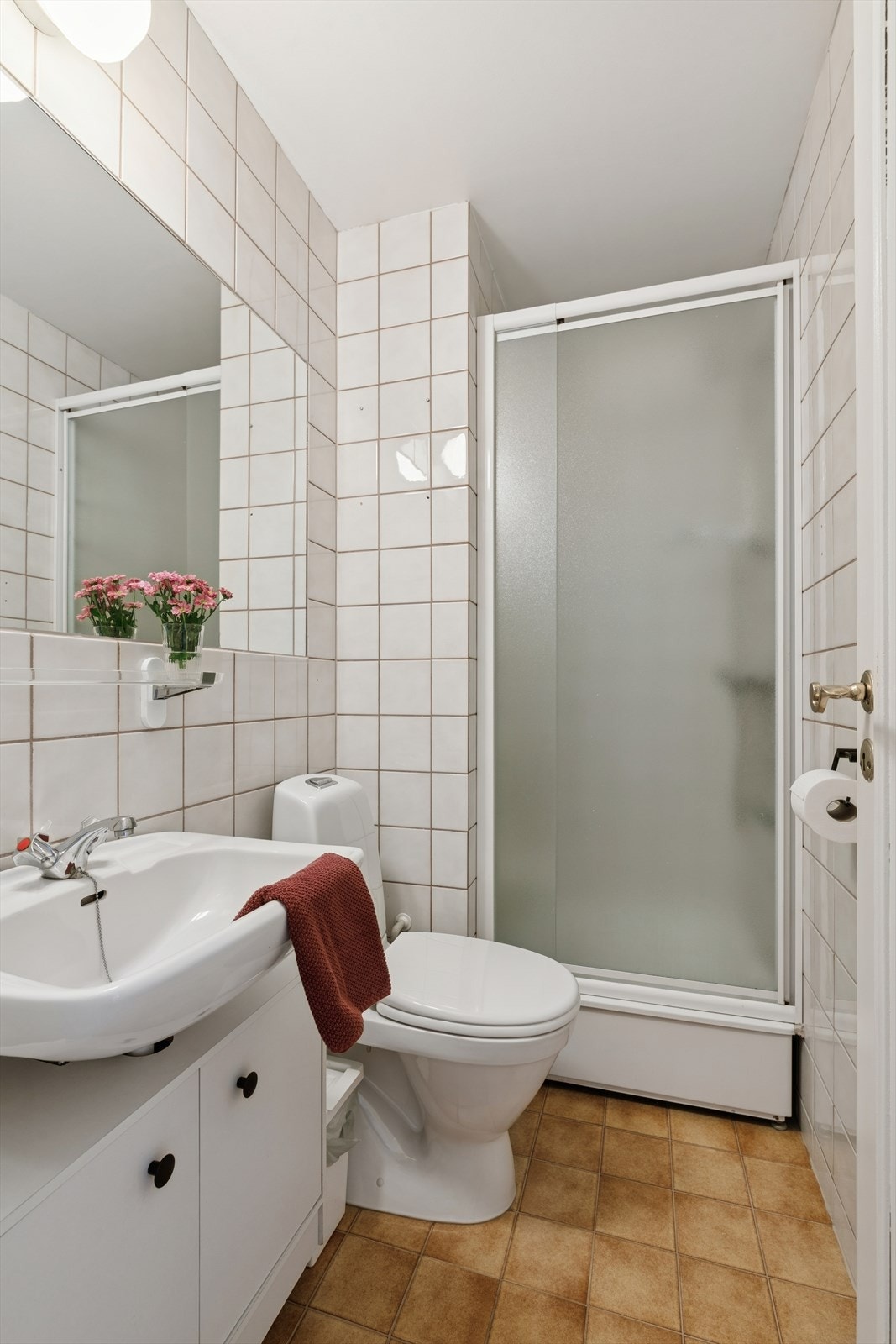 Baderom nr. 2 er fra byggeåret og har flislagt gulv og vegger. Rommet er utstyrt med et dusjkar med innfellbar dør, servant i benkeskap med glatte fronter, og et gulvstående toalett. Galleribilde