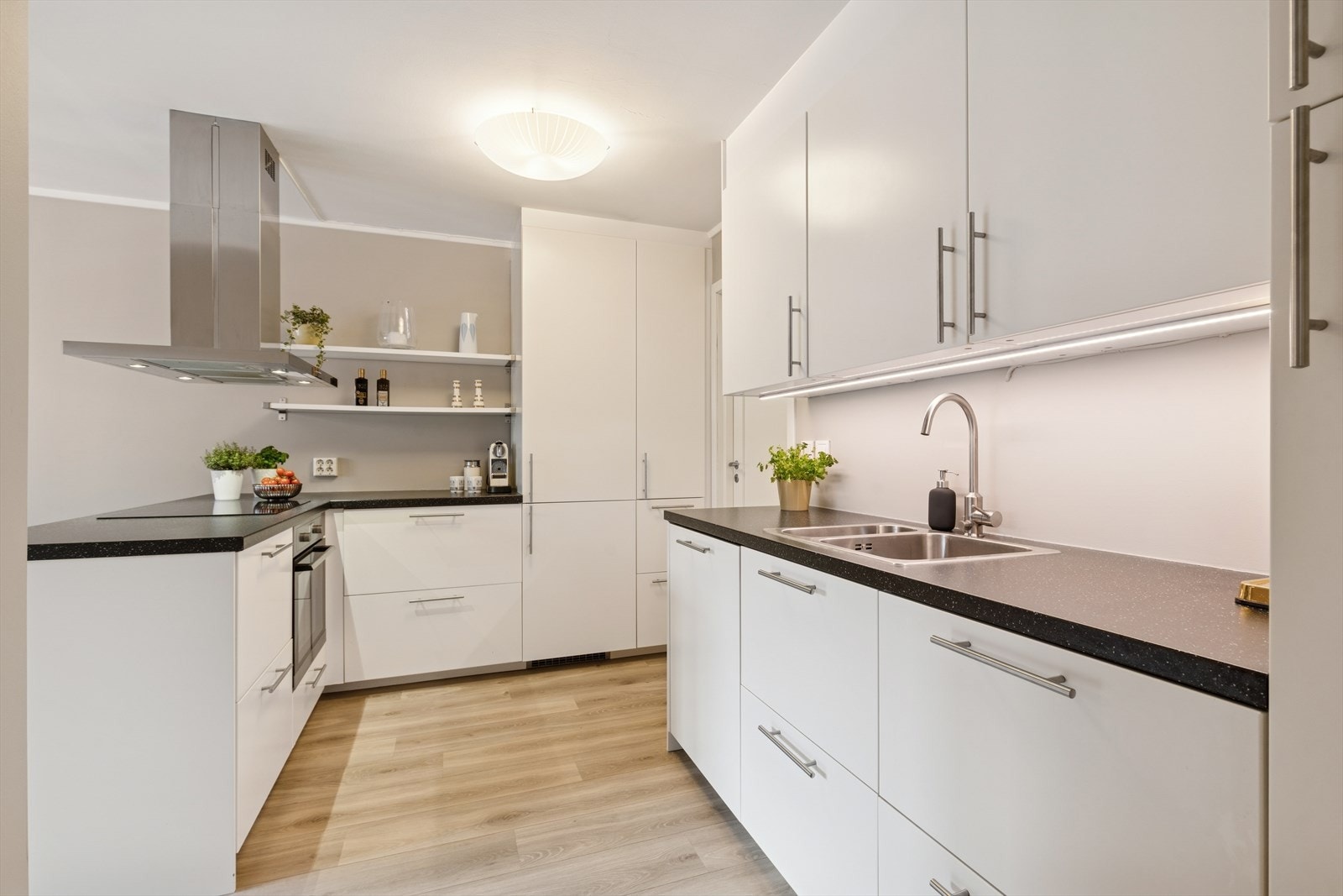 Kjøkkenet har en innredning med glatte fronter og en benkeplate av laminat, samt integrerte hvitevarer som kjøl/fryseskap, oppvaskmaskin, induksjonstopp og stekeovn. Galleribilde