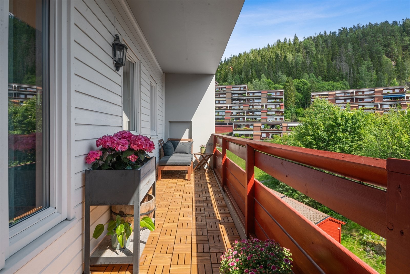 Verandaen ut fra kjøkkenet har utsikt over grøntområder og omkringliggende bebyggelse. Galleribilde