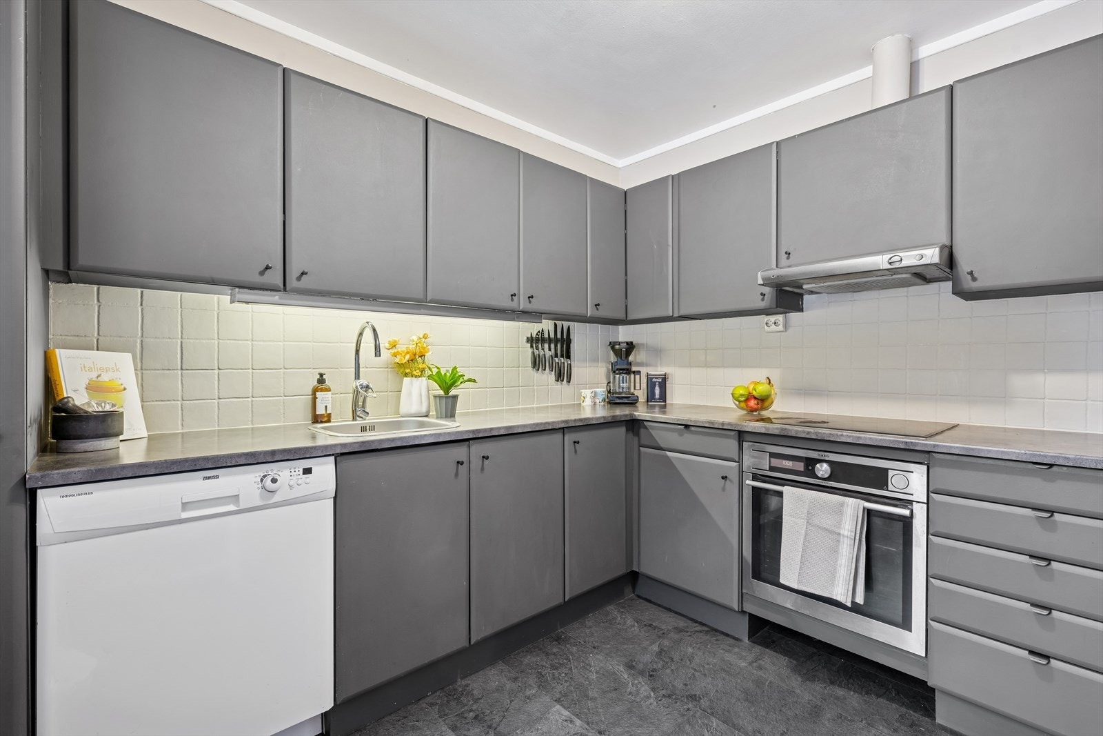 Kjøkkeninnredning med malte fronter, laminatbenkeplate og integrert stekeovn og platetopp. Galleribilde