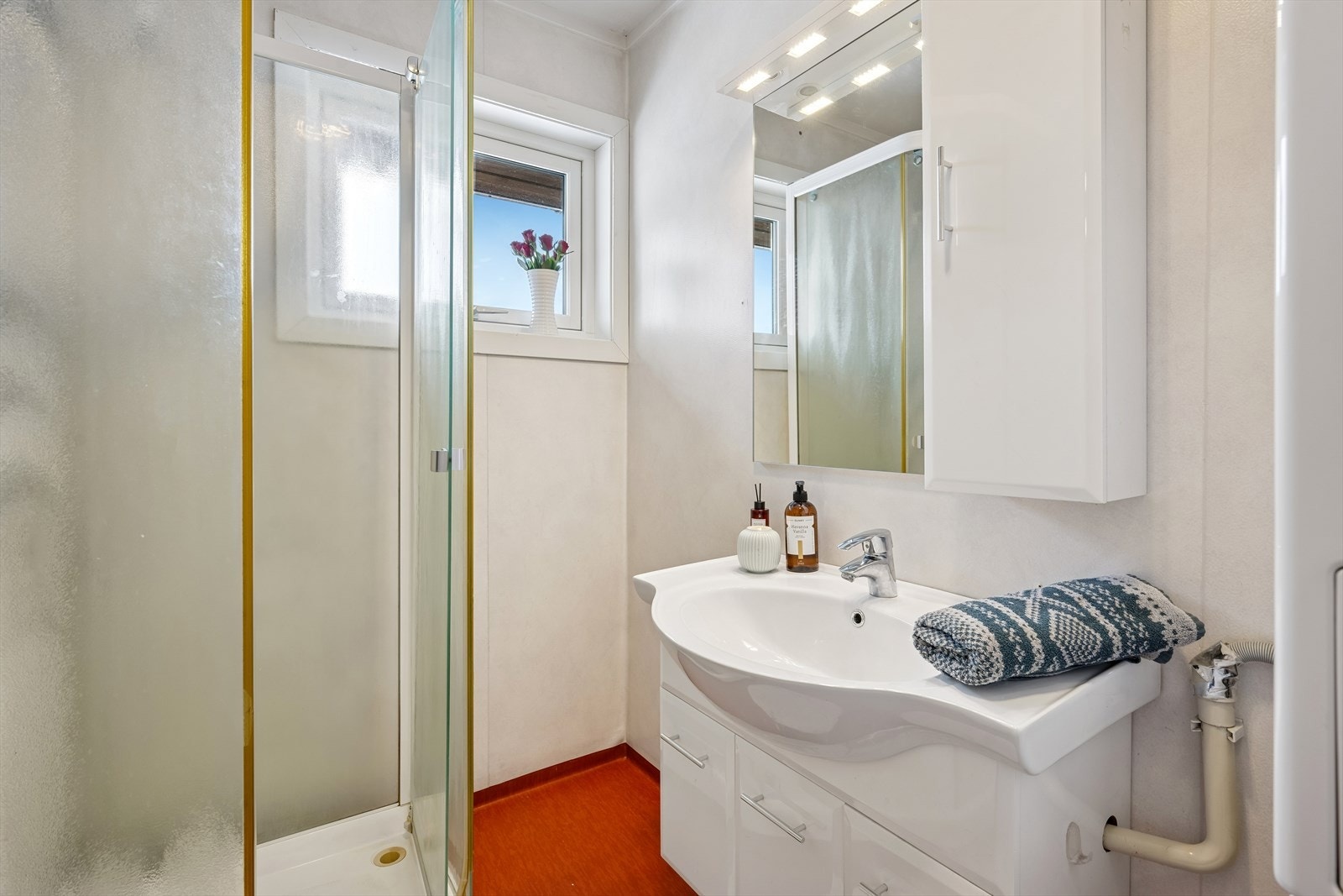 Badet er utstyrt med dusjkabinett og servant i innredning. Oppvarming via panelovn. Galleribilde