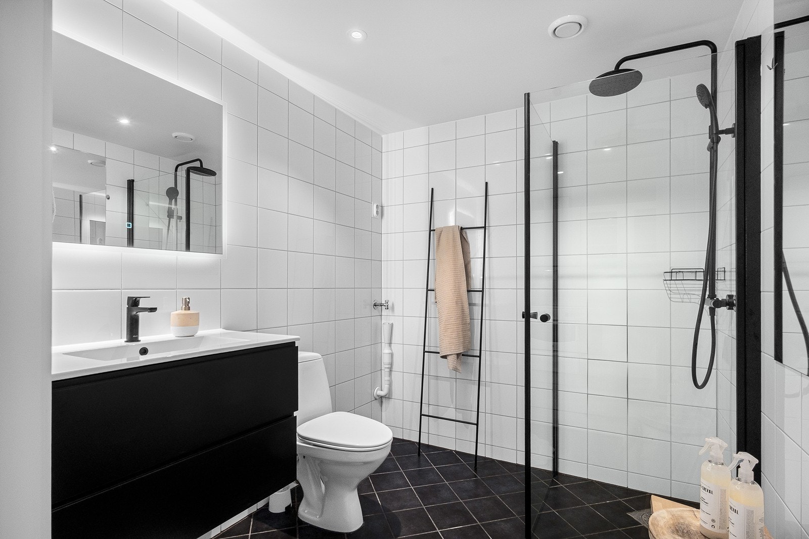 Badet har hvite flislagte vegger og sorte gulvfliser med behagelig gulvvarme. Badet ble modernisert i 2026 med nytt baderomsinventar. Galleribilde