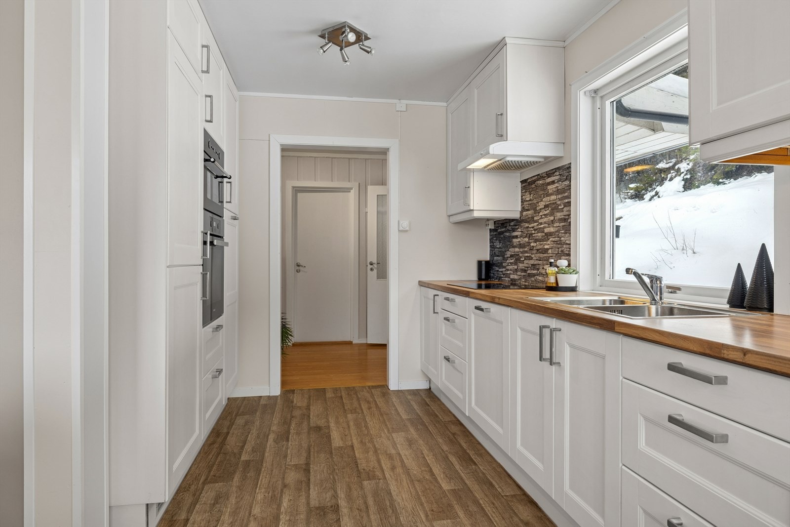 Kjøkkenet i første etasje fremstår lyst, pent og moderne, og danner et naturlig samlingspunkt i boligen. Innredningen er fra 2022 og er utformet i en praktisk vinkel mot spiseplassen, med en åpen løsning videre mot den nedsenkede stuedelen. Galleribilde