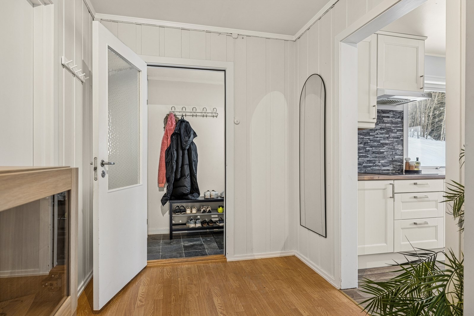 Videre inn i boligen kommer du til en mellomgang som fungerer som et praktisk knutepunkt. Herfra fordeler planløsningen seg videre til to av boligens romslige soverom, baderommet samt kjøkken- og spisestuedelen. Galleribilde