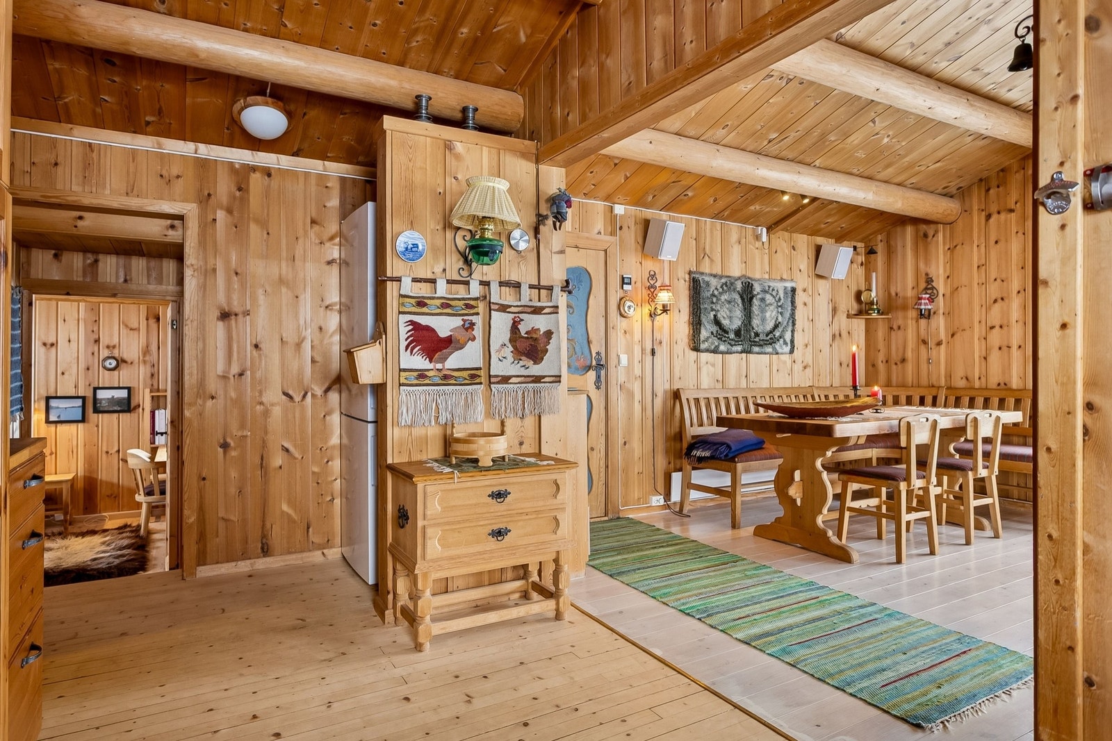 Spiestue sett fra kjøkkenet med døråpningen inn til soverom 1 i hovedhytta. Kjøl/frys som tåler -15 grader er plassert bak halvvegg. Galleribilde