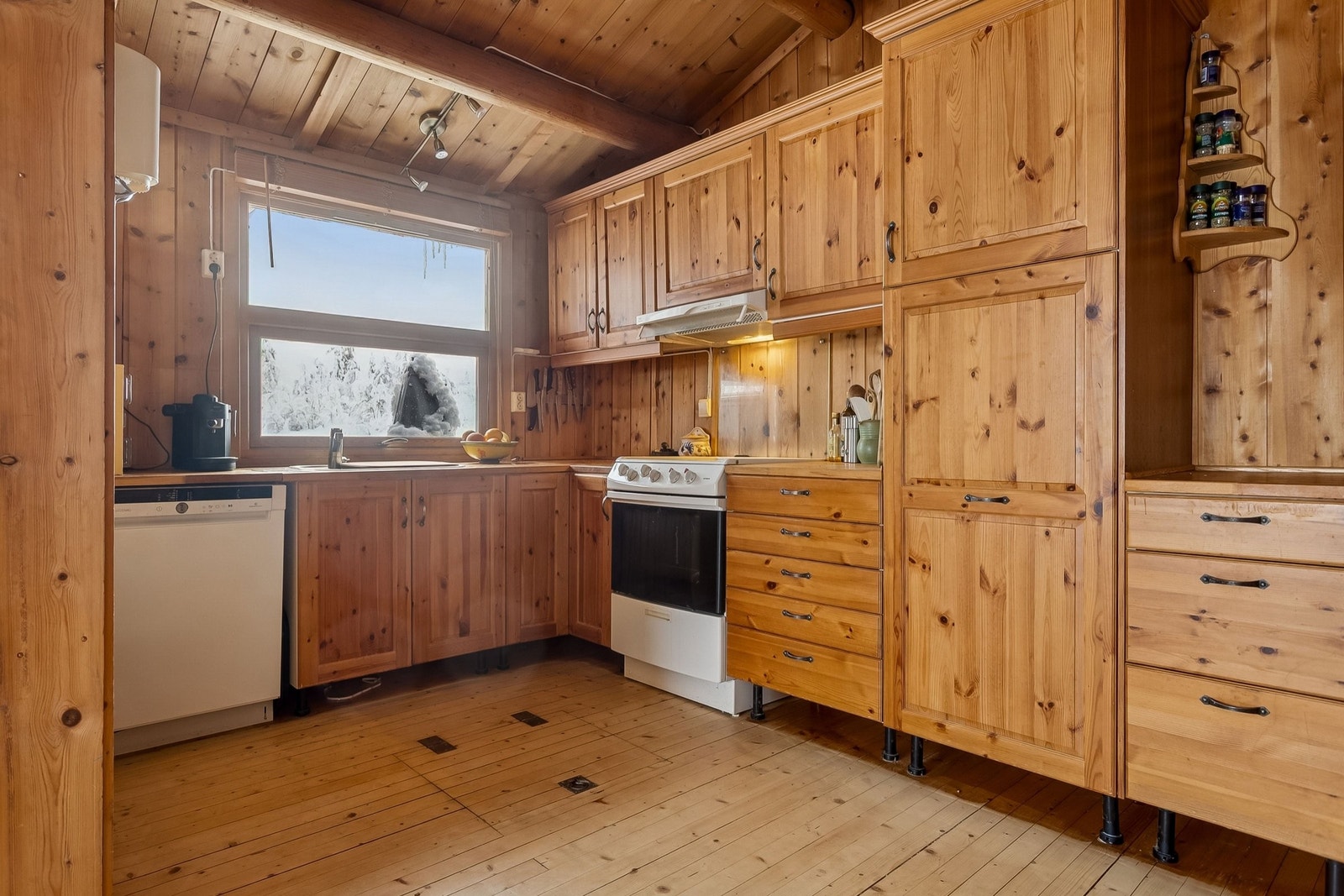 Kjøkkeninnredning i helfuru. Oppvaskmaskin og komfyr med keramisk plate. Galleribilde