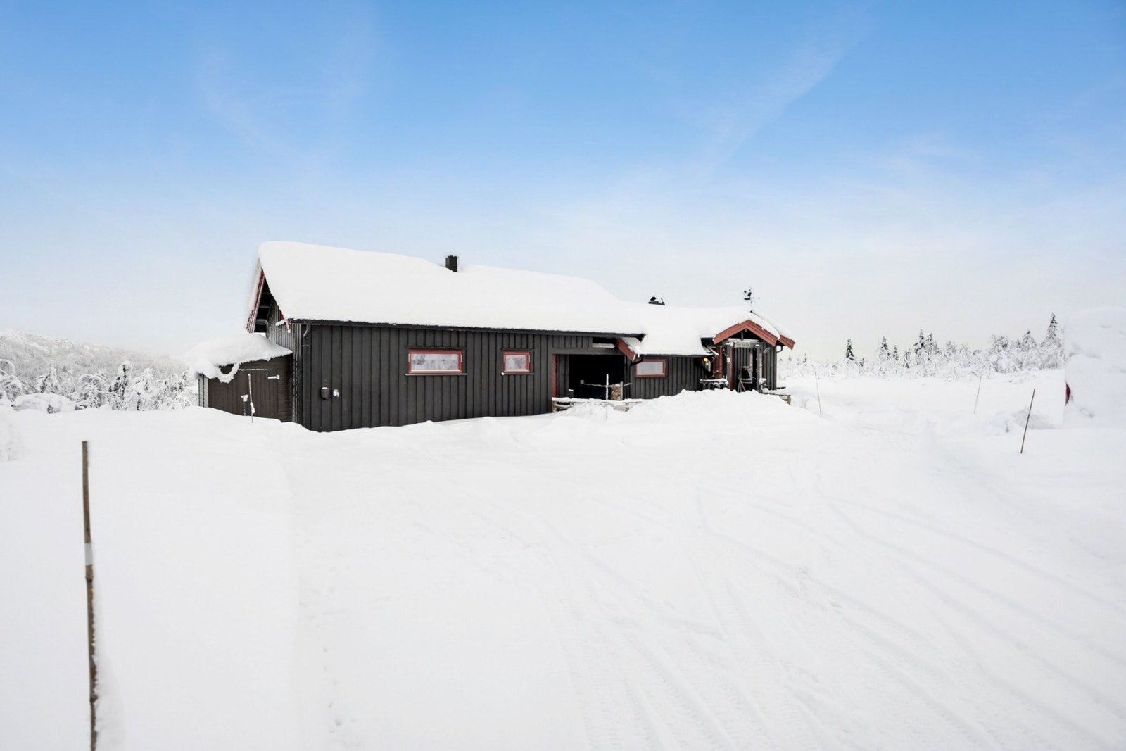 Hytta sett fra innkjørsel med tilbygget i front med ladepunkt for el-bil. Galleribilde