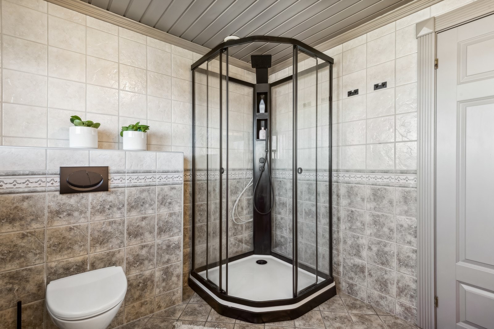 Baderommet består blant annet av veggfestet klosett, dusjkabinett og nedfelt servant med tilhørende skuffeseksjon. Galleribilde