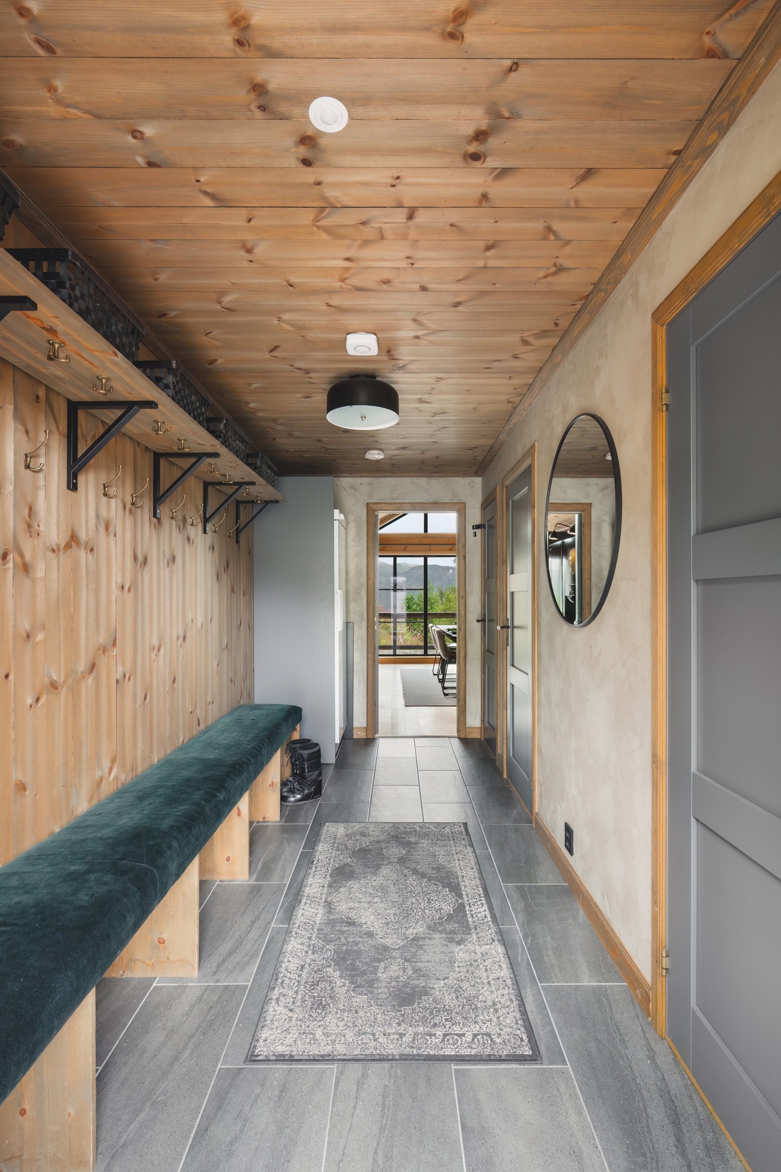 Romslig gang med fliser på gulv, kalkmaling og sealer på vegg. God plass til å henge fra deg yttertøy i tillegg til tørkeskap. Galleribilde