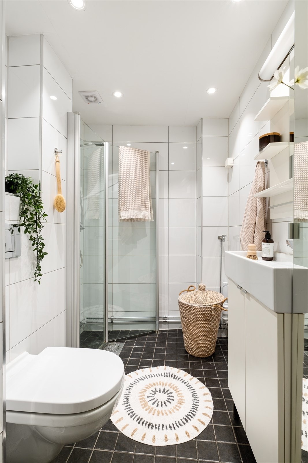 Flislagt baderom med elektrisk avtrekk, speil + speilskap, armatur, downlights, opplegg for vaskemaskin, servant med innredning, dusj hjørne med innfellbare glassdører, vegghengt toalett. Galleribilde